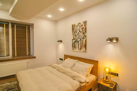 Jaukus miegamasis su patogia lova ir šiltu apšvietimu