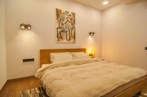 Jaukus miegamasis su patogia lova ir šiltu apšvietimu