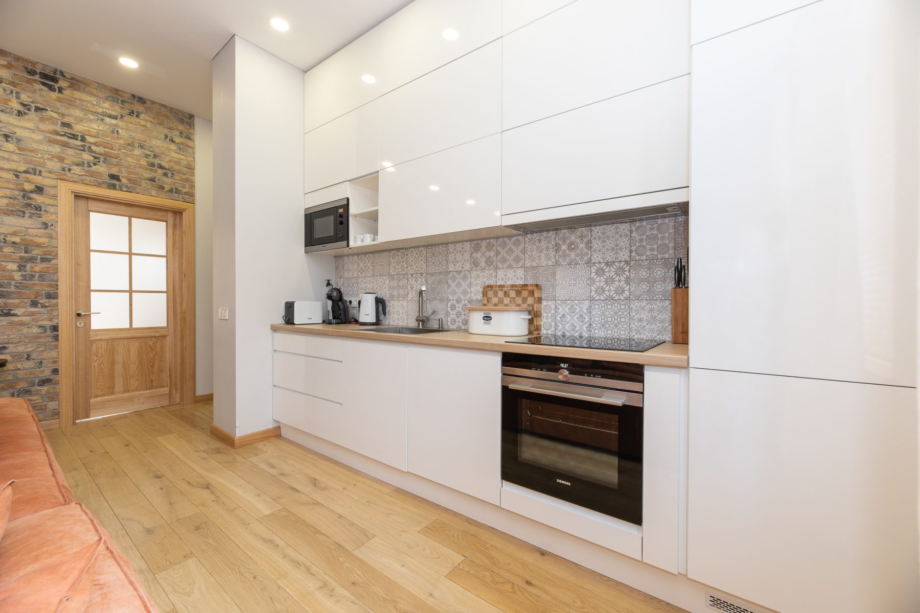 Šviesi virtuvė su moderniais baldais ir valgomojo vieta