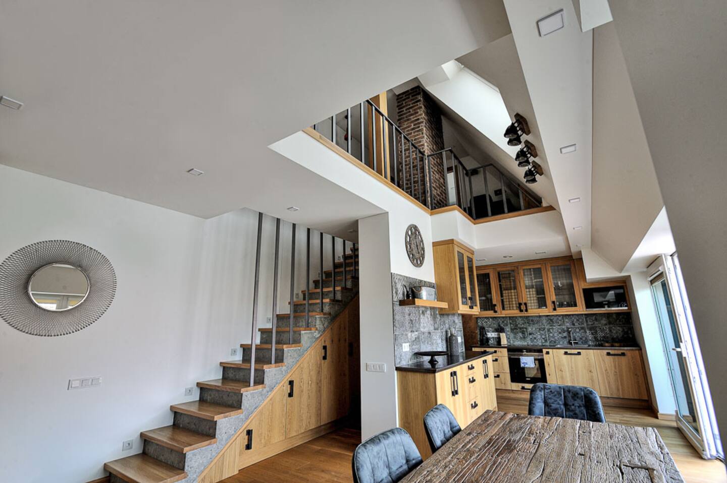 Erdvi svetainė su sofa, laiptais ir natūralia šviesa