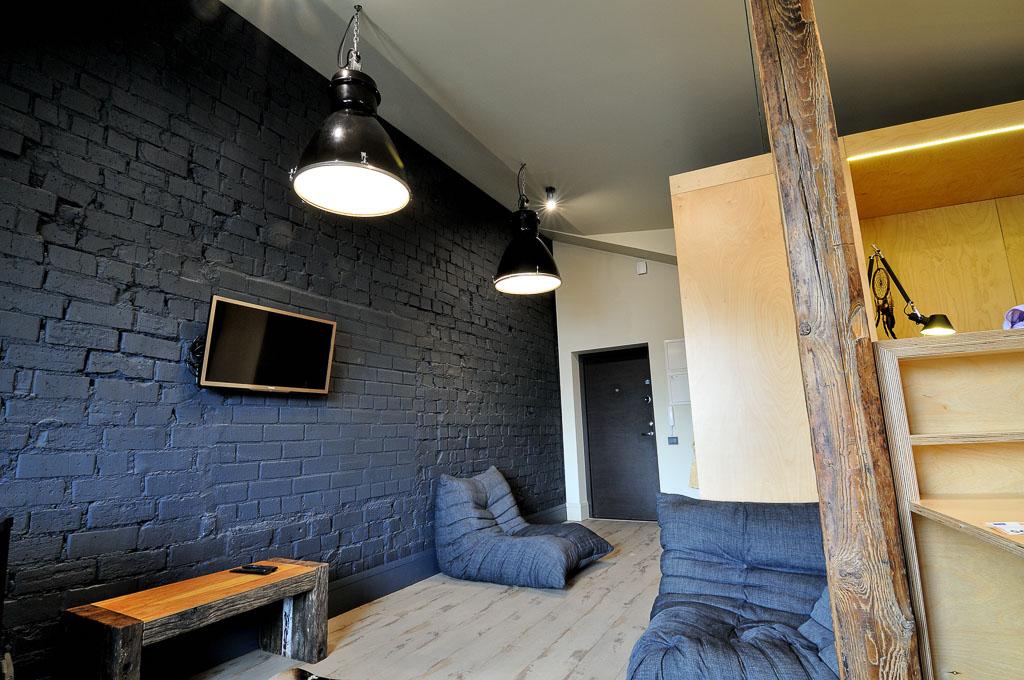 Industrinio stiliaus svetainė su sofa ir poilsio zona