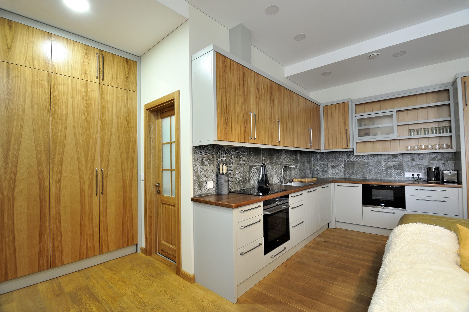 Modernus svetainės ir virtuvės interjeras su atvira erdve ir medinėmis grindimis