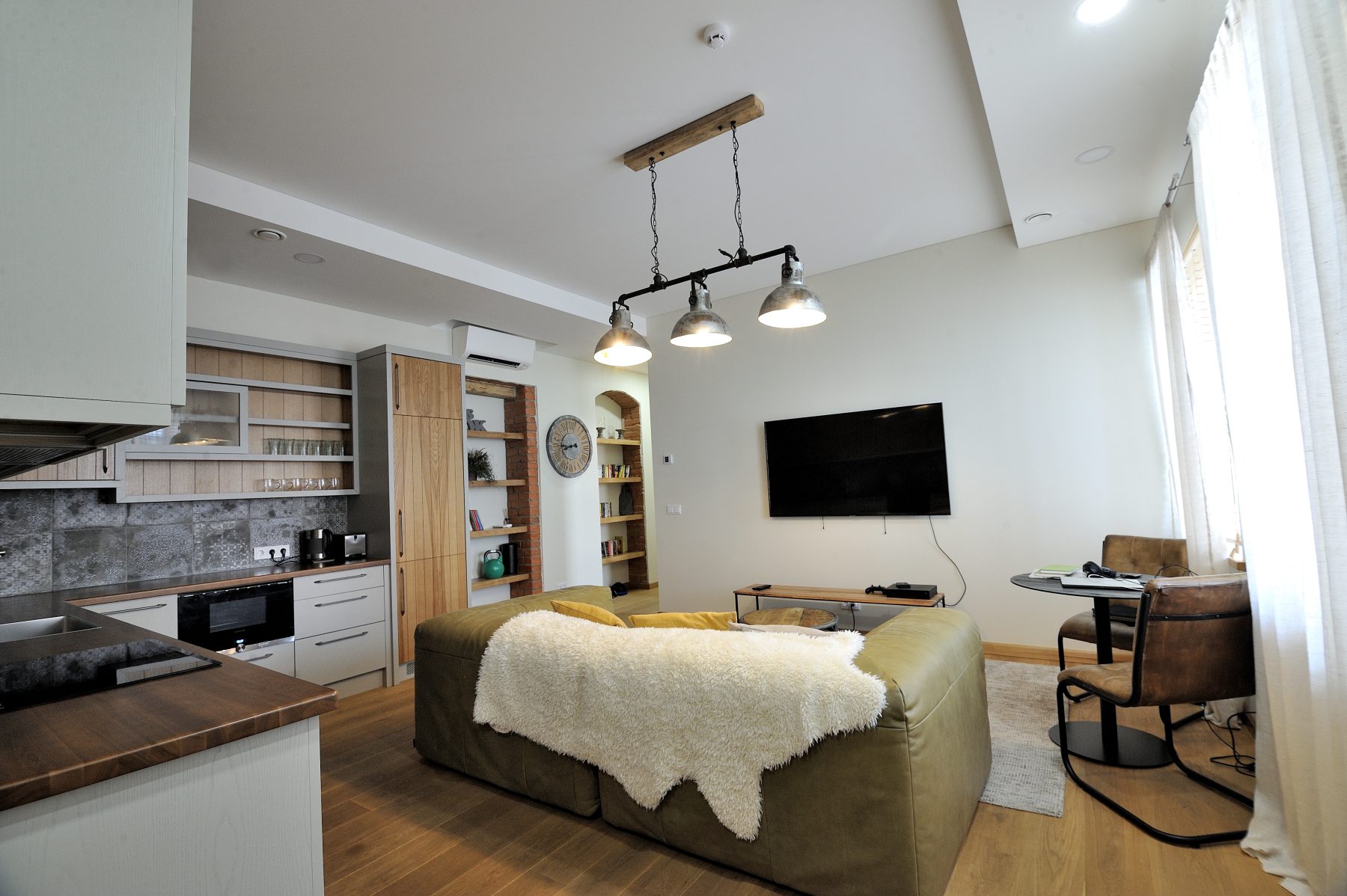 Modernus svetainės ir virtuvės interjeras su atvira erdve ir medinėmis grindimis