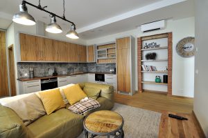 Modernus svetainės ir virtuvės interjeras su atvira erdve ir medinėmis grindimis