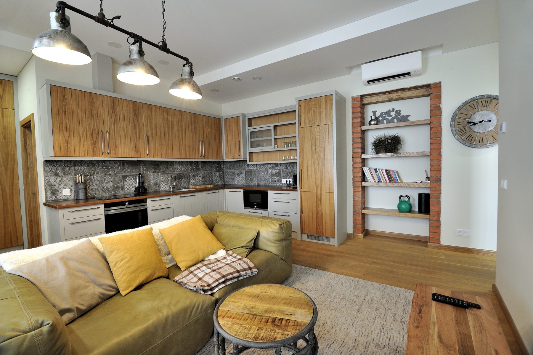 Modernus svetainės ir virtuvės interjeras su atvira erdve ir medinėmis grindimis