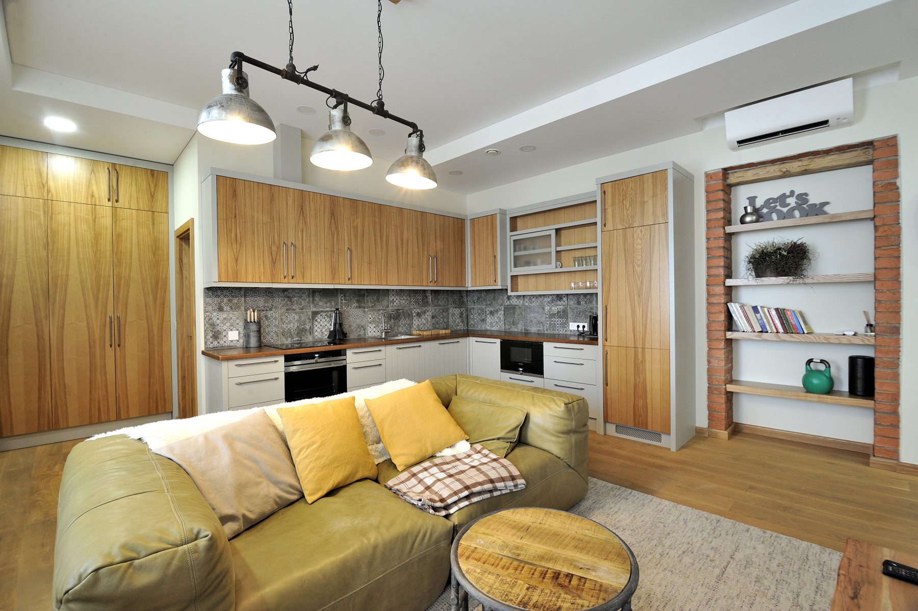 Modernus svetainės ir virtuvės interjeras su atvira erdve ir medinėmis grindimis