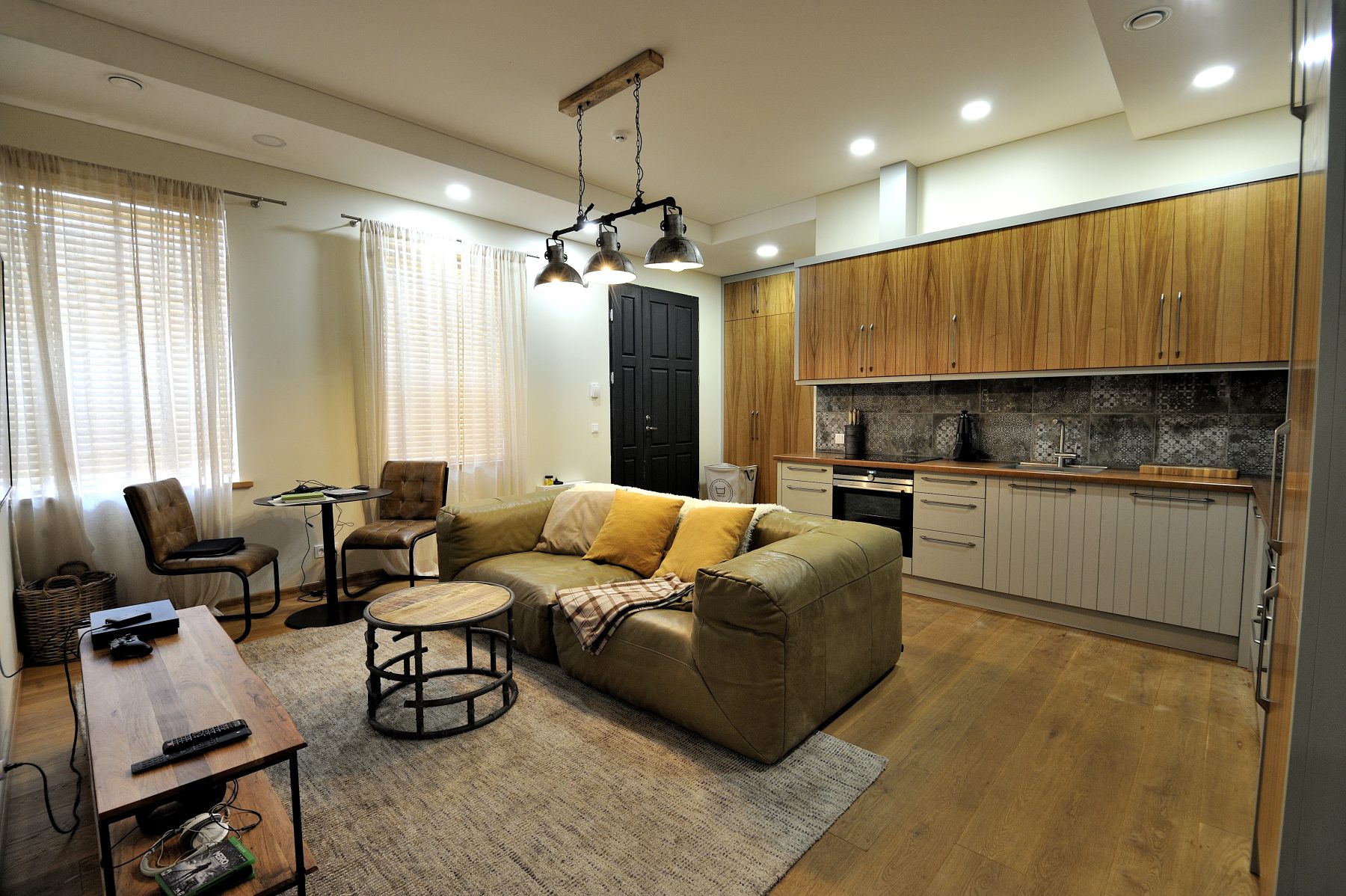 Modernus svetainės ir virtuvės interjeras su atvira erdve ir medinėmis grindimis