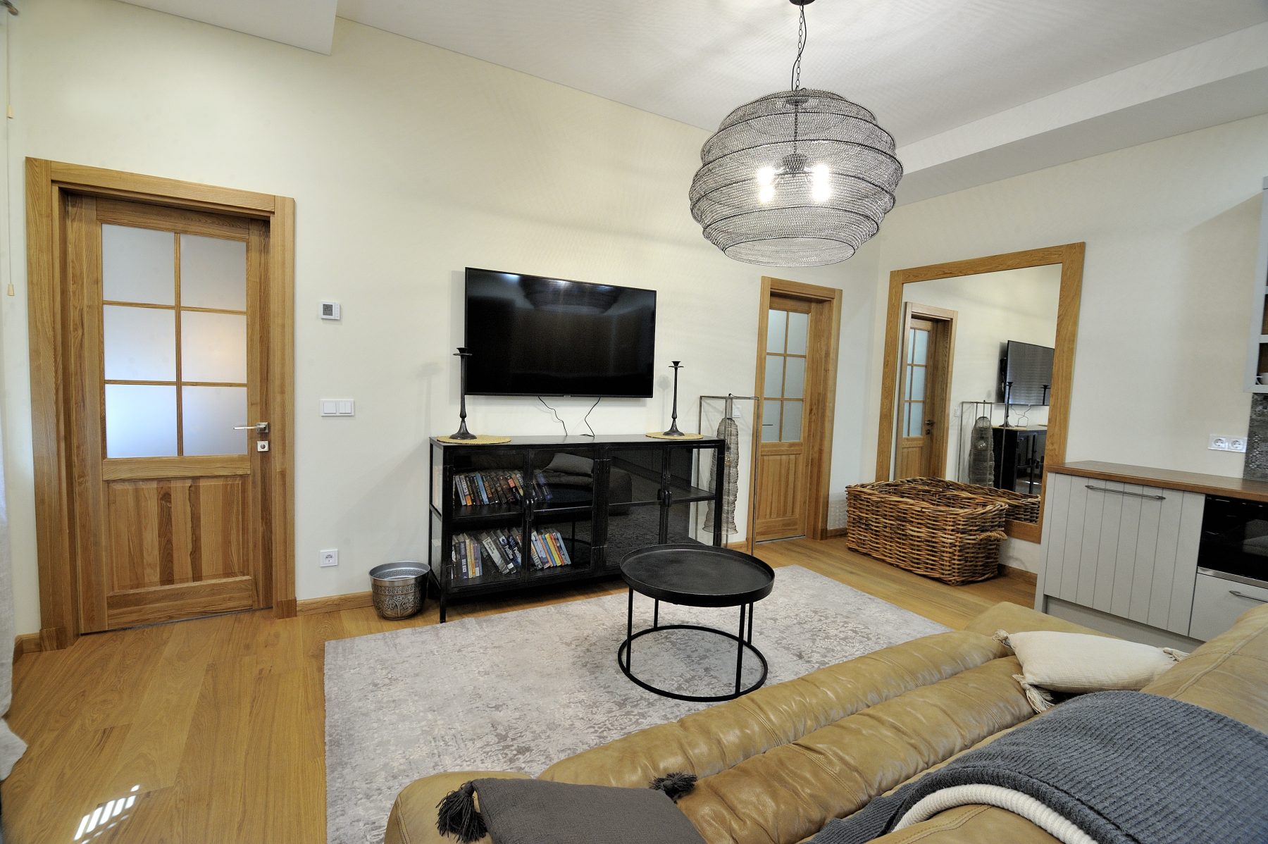 Šviesi svetainė su sofa, televizoriumi ir moderniu interjeru