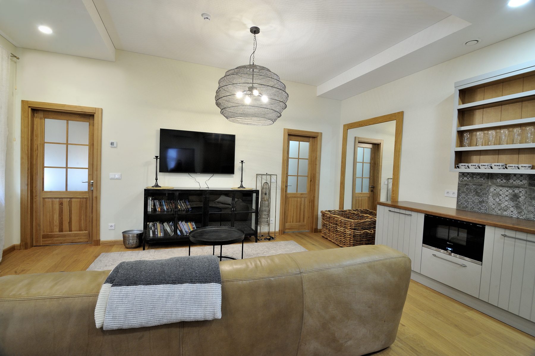 Šviesi svetainė su sofa, televizoriumi ir moderniu interjeru