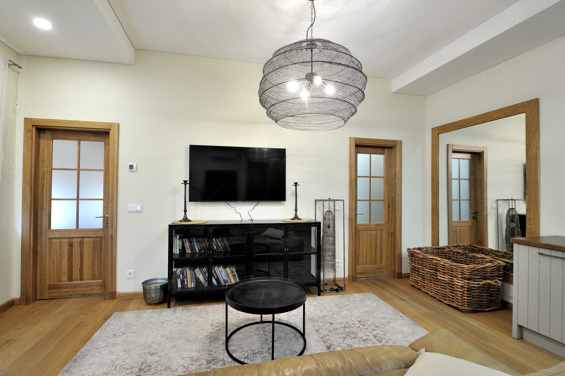 Šviesi svetainė su sofa, televizoriumi ir moderniu interjeru