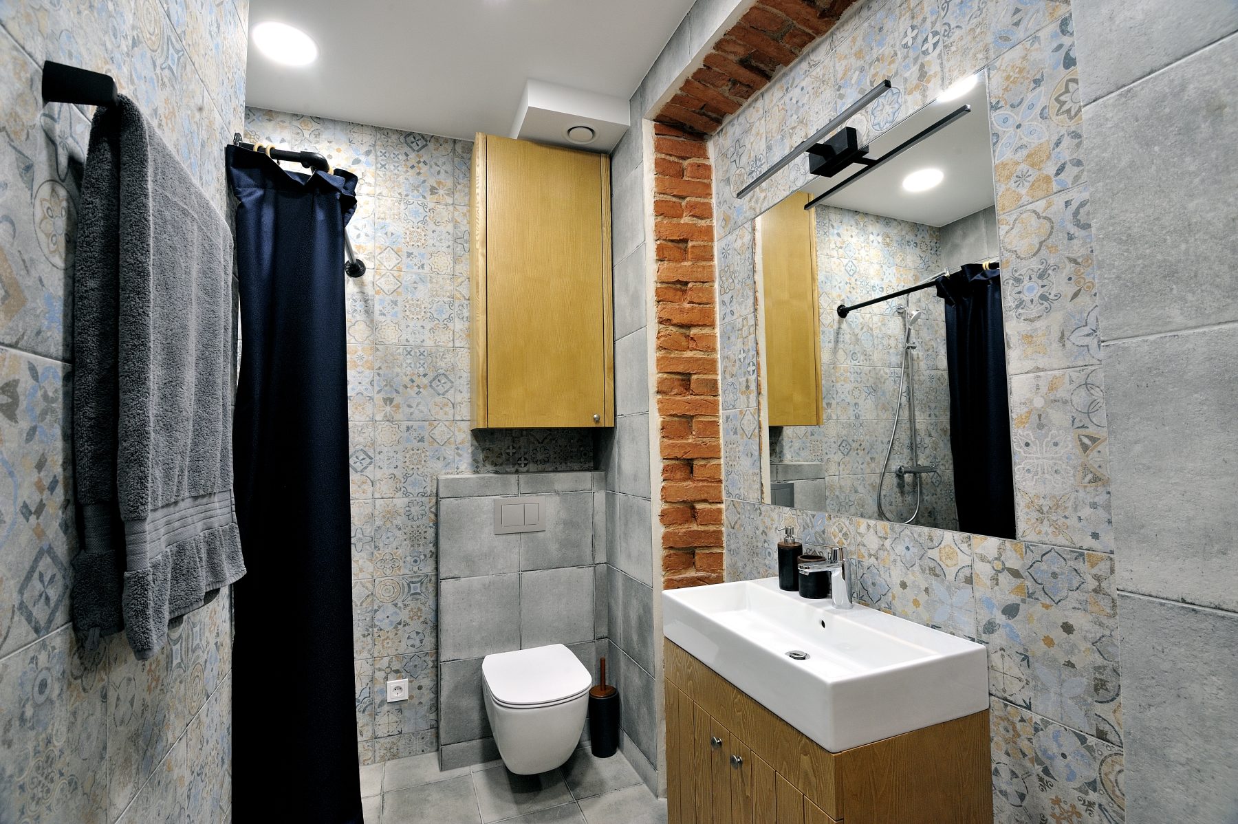 Modernus vonios kambarys su dušu, medinėmis spintelėmis ir dekoratyvinėmis plytelėmis