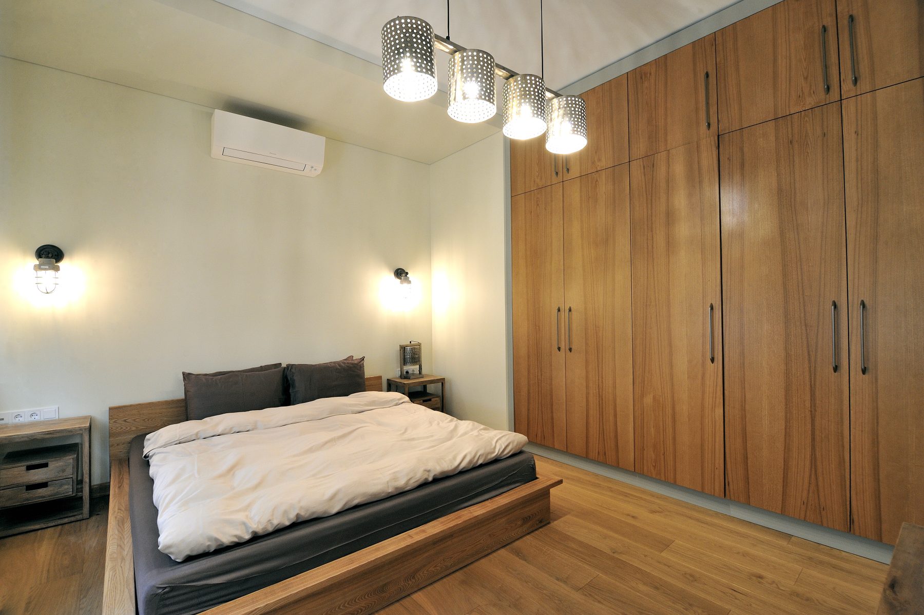 Šviesus miegamasis su didelėmis integruotomis spintomis ir medinėmis grindimis
