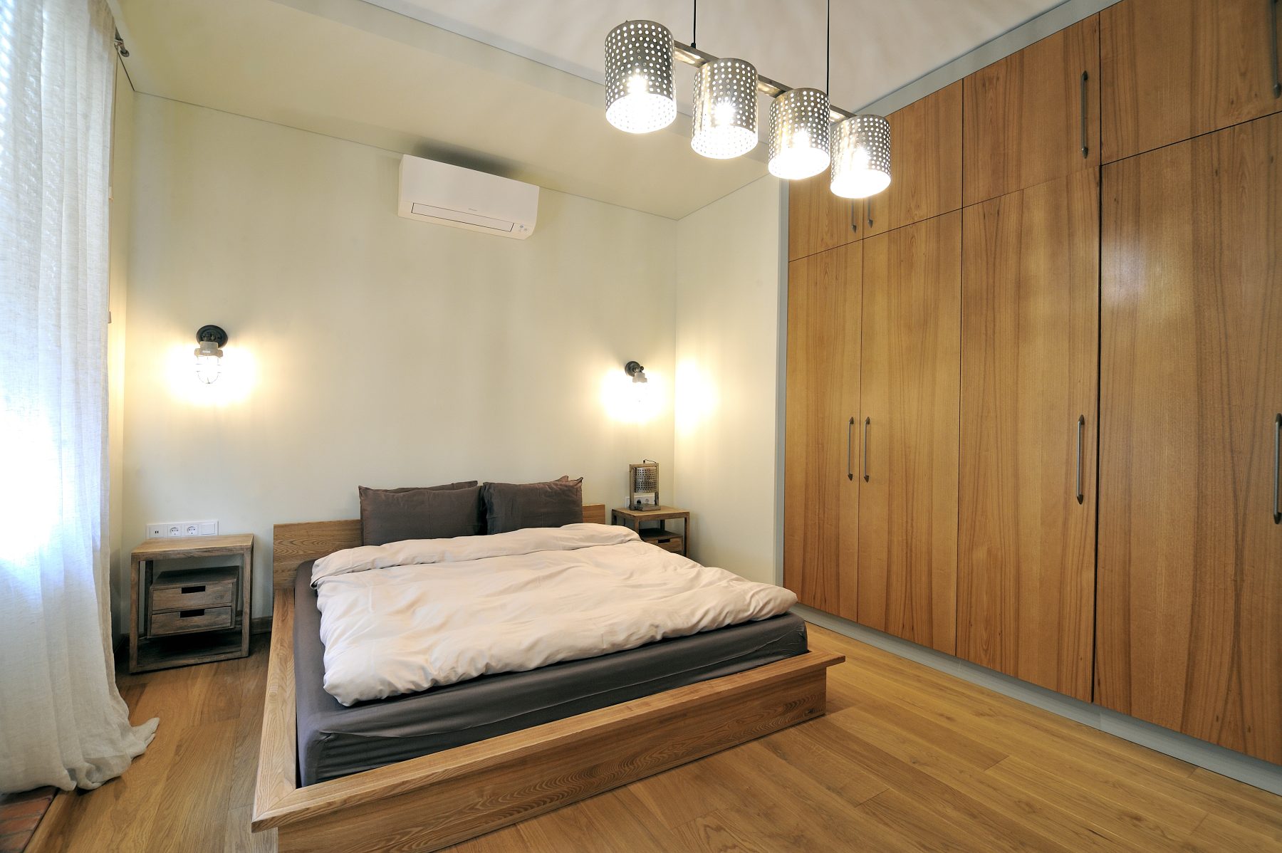 Šviesus miegamasis su didelėmis integruotomis spintomis ir medinėmis grindimis