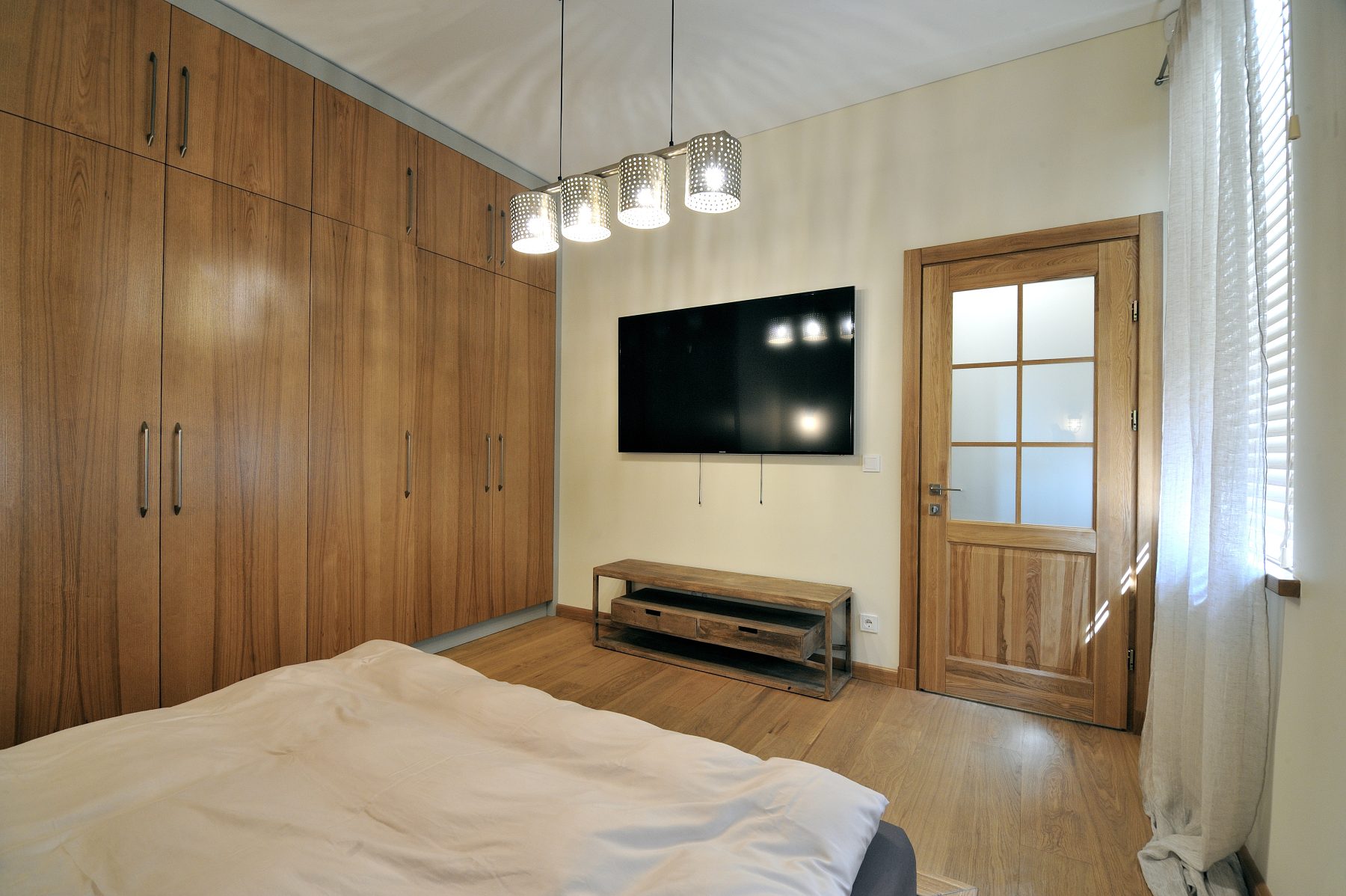 Šviesus miegamasis su didelėmis integruotomis spintomis ir medinėmis grindimis