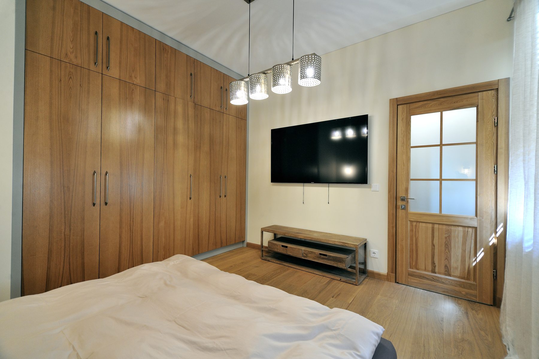 Šviesus miegamasis su didelėmis integruotomis spintomis ir medinėmis grindimis