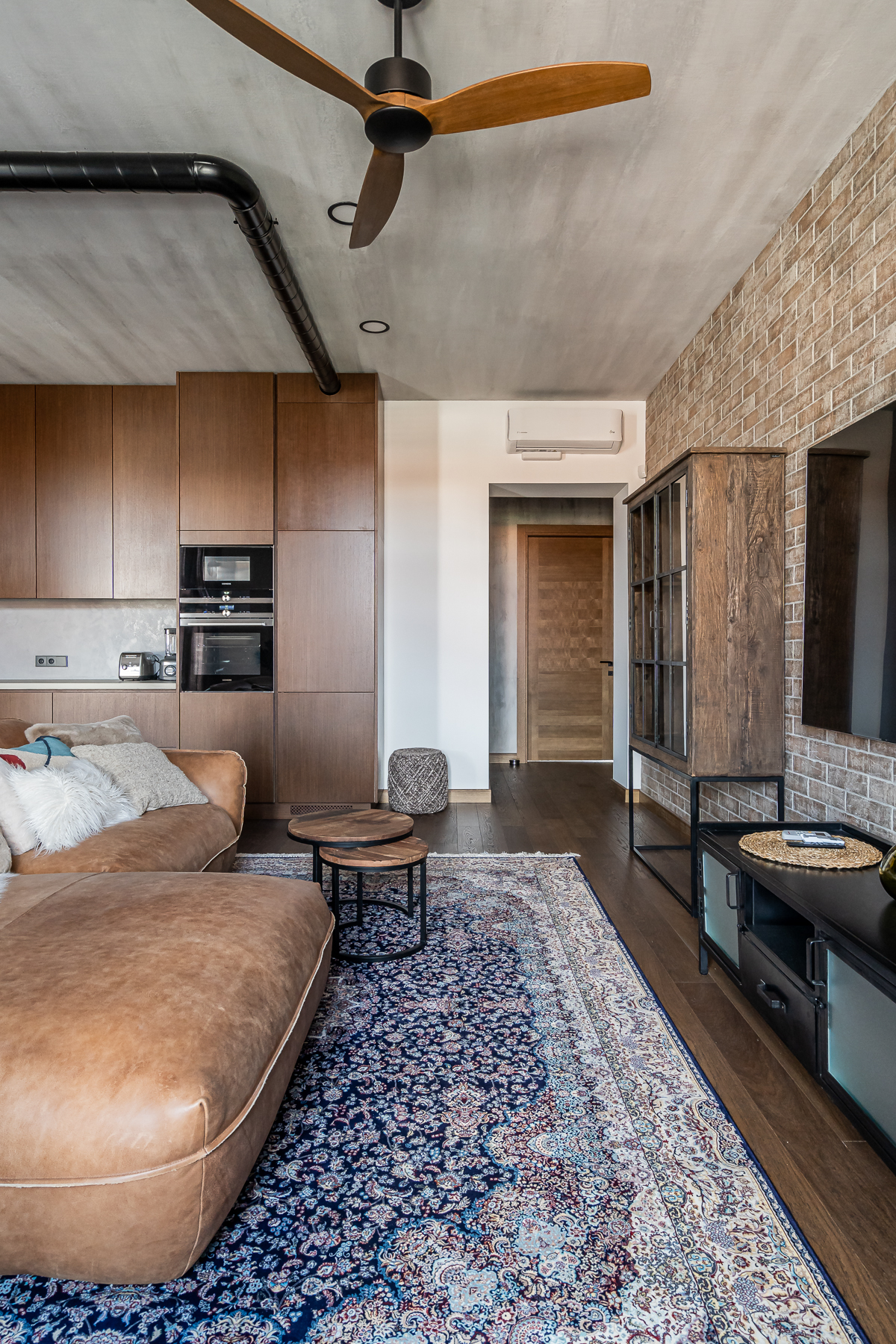 Šviesi svetainė su minkštais baldais ir senamiesčio vaizdu pro langus