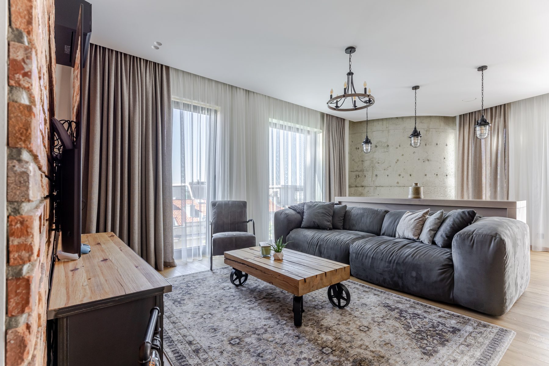 Moderni svetainė su dizaino baldais ir dideliais langais