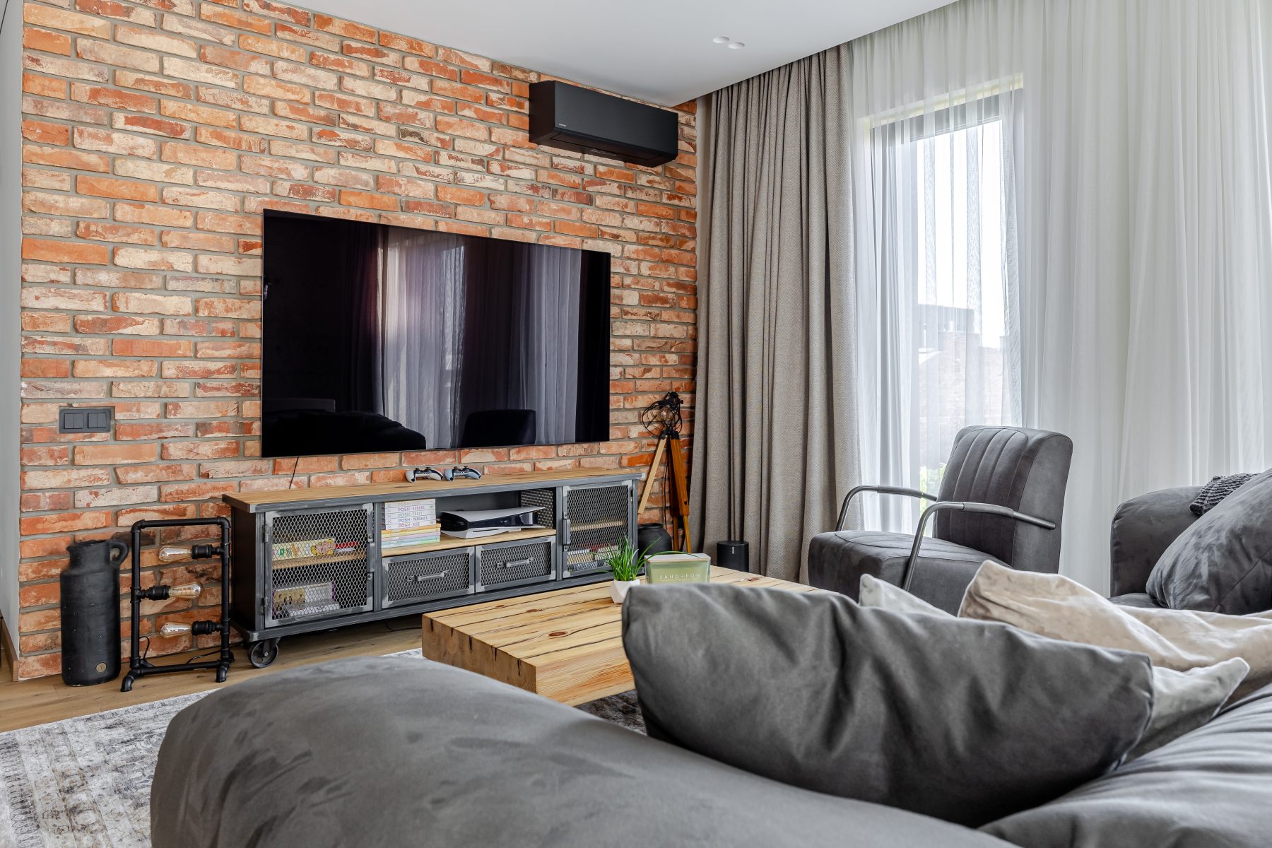 Moderni svetainė su dizaino baldais ir dideliais langais