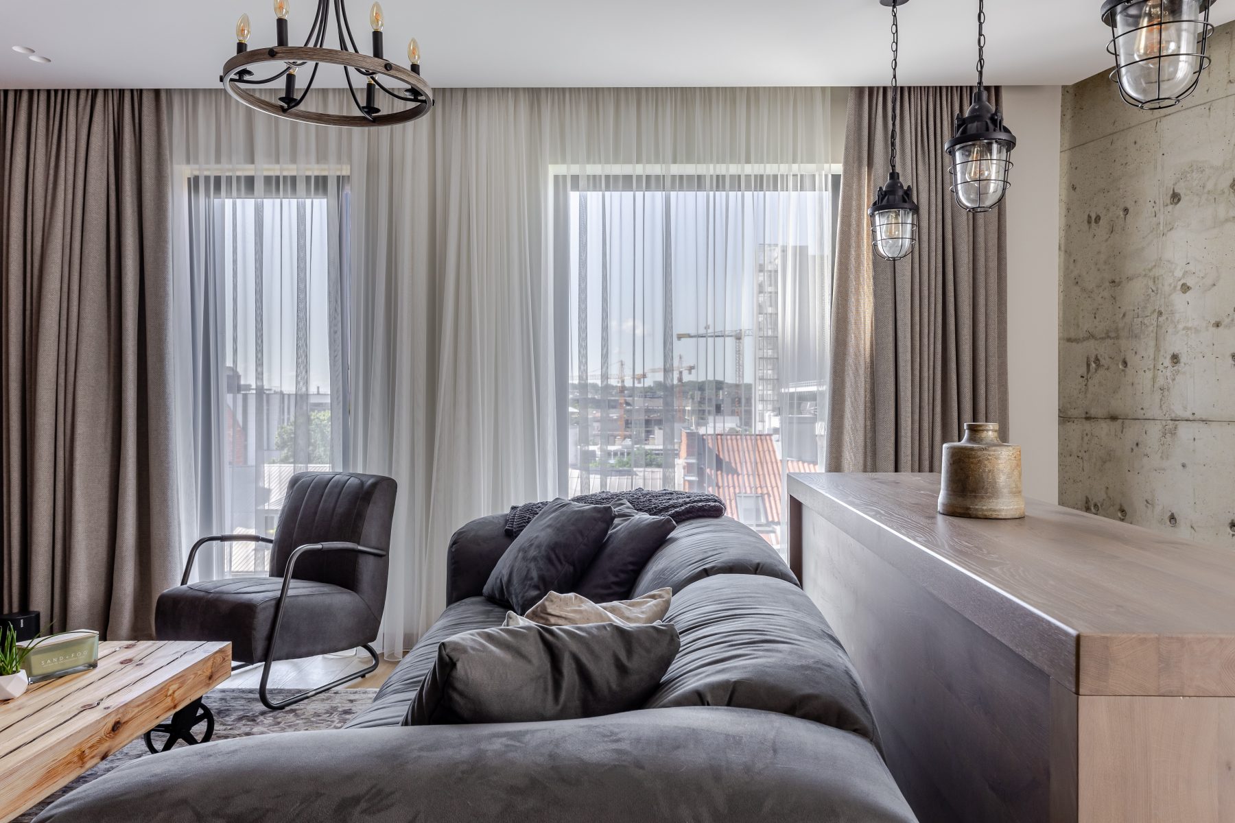 Moderni svetainė su dizaino baldais ir dideliais langais