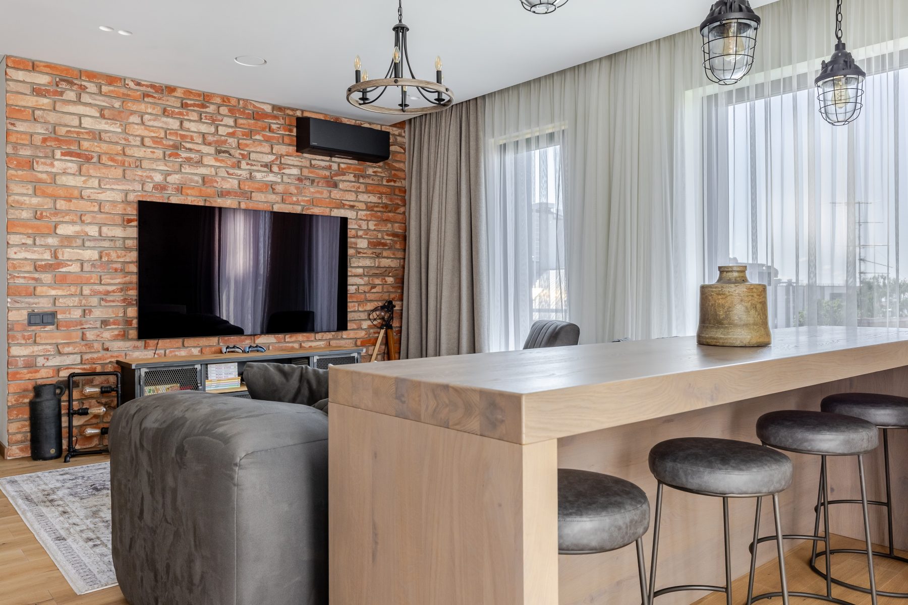 Moderni svetainė su dizaino baldais ir dideliais langais