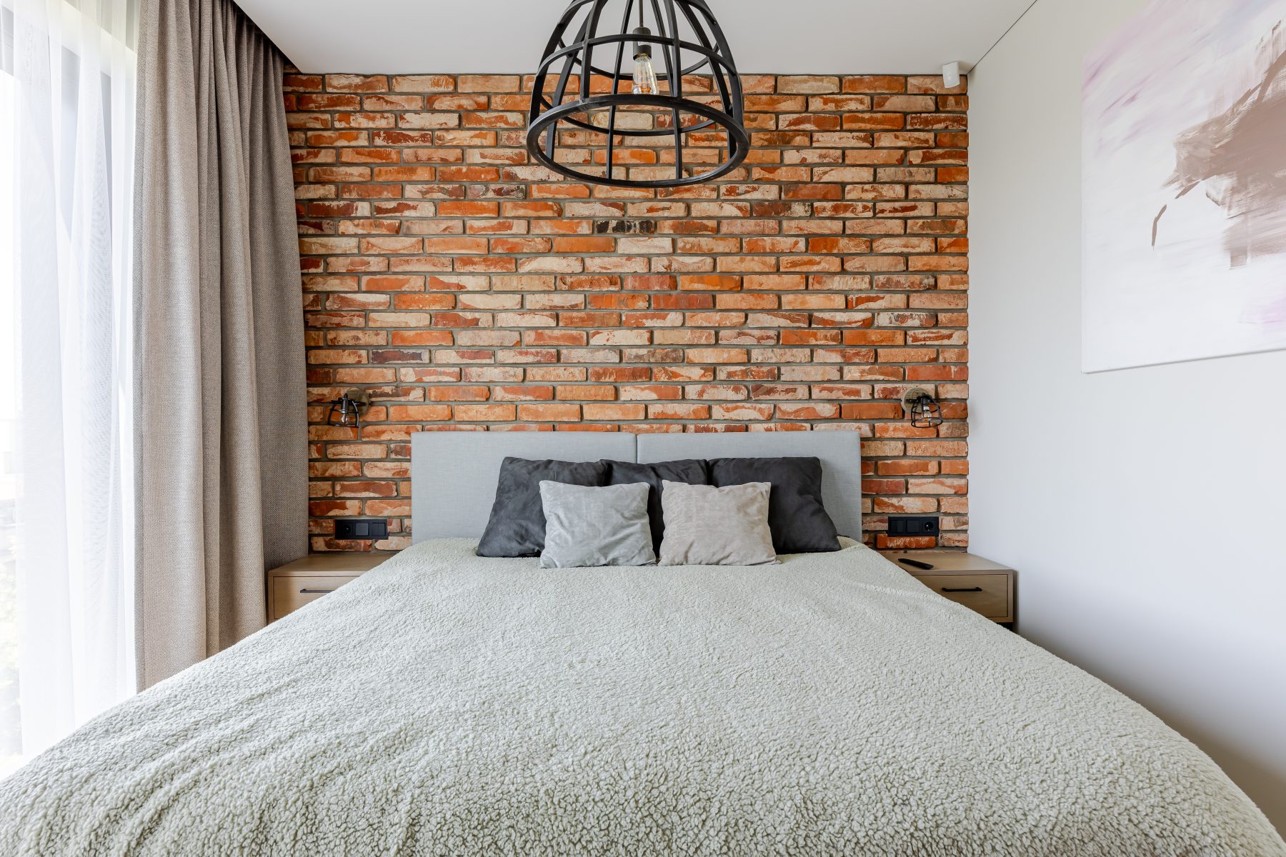 Miegamasis su natūralių plytų siena ir dideliais langais