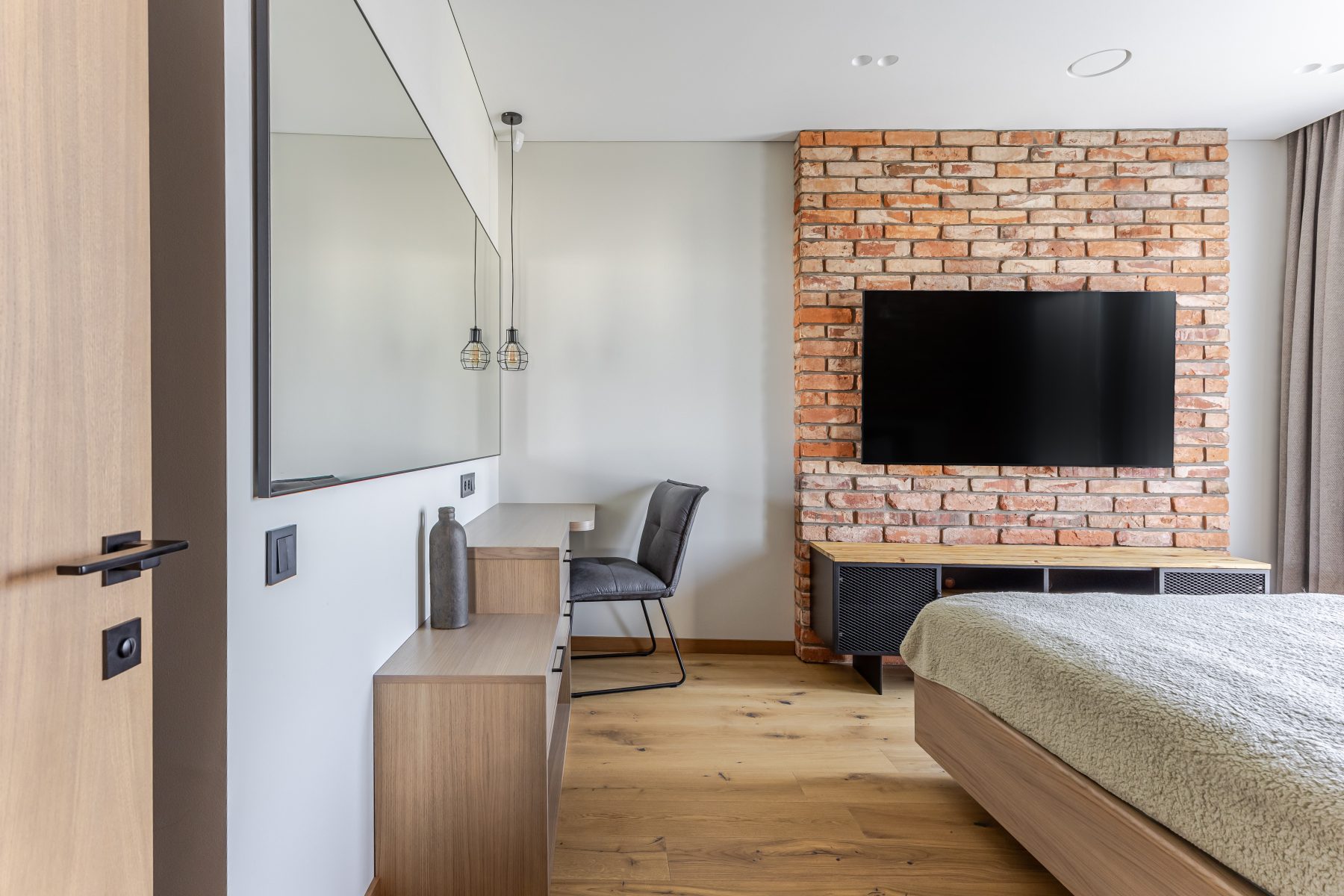 Miegamasis su natūralių plytų siena ir dideliais langais