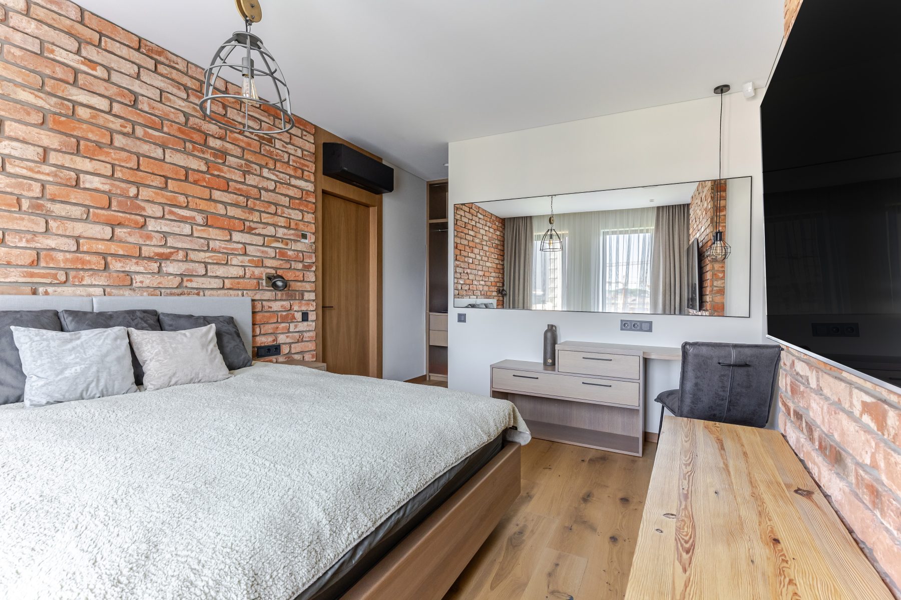 Miegamasis su natūralių plytų siena ir dideliais langais