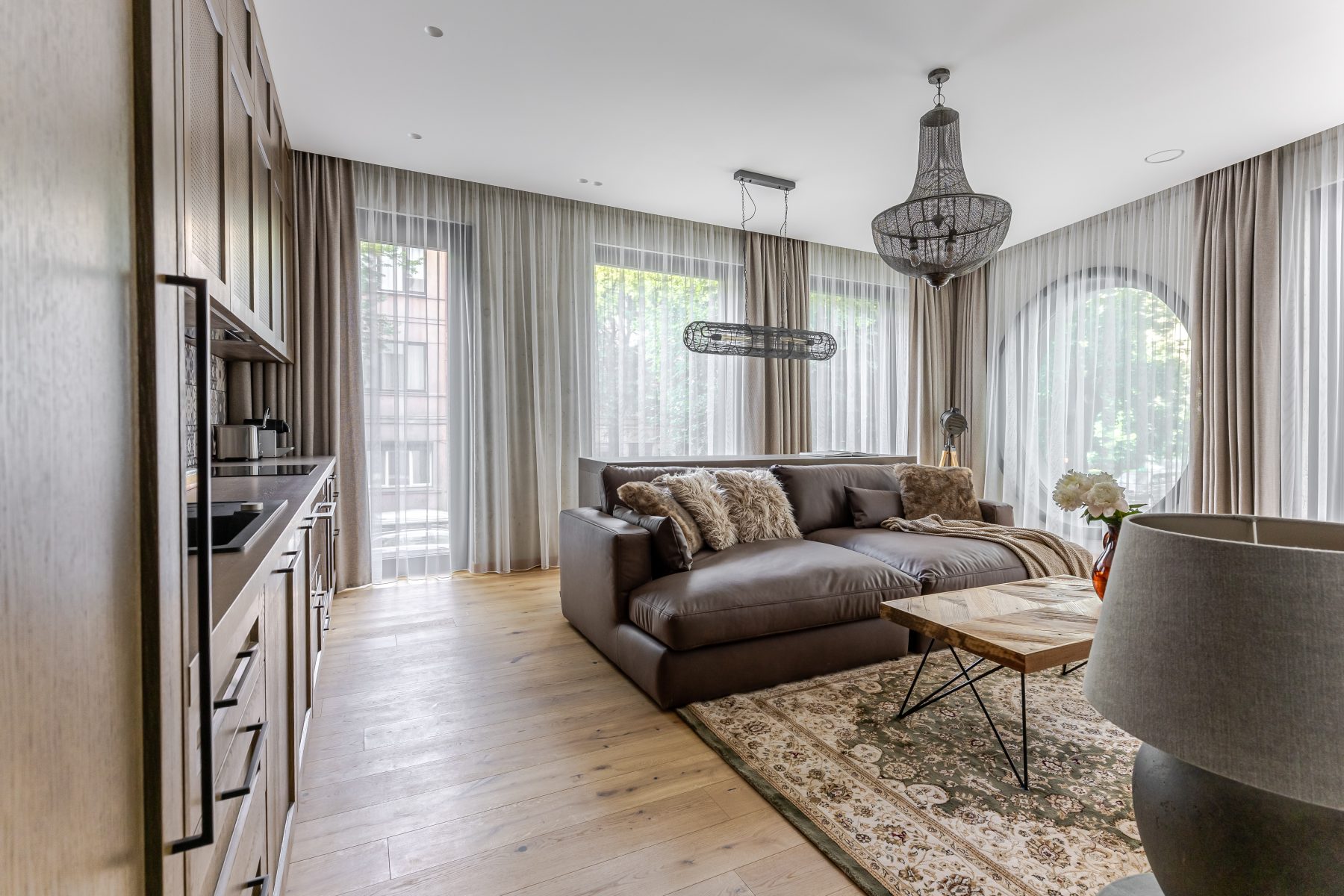 Šviesi moderni svetainė su dideliais langais ir natūralaus medžio detalėmis