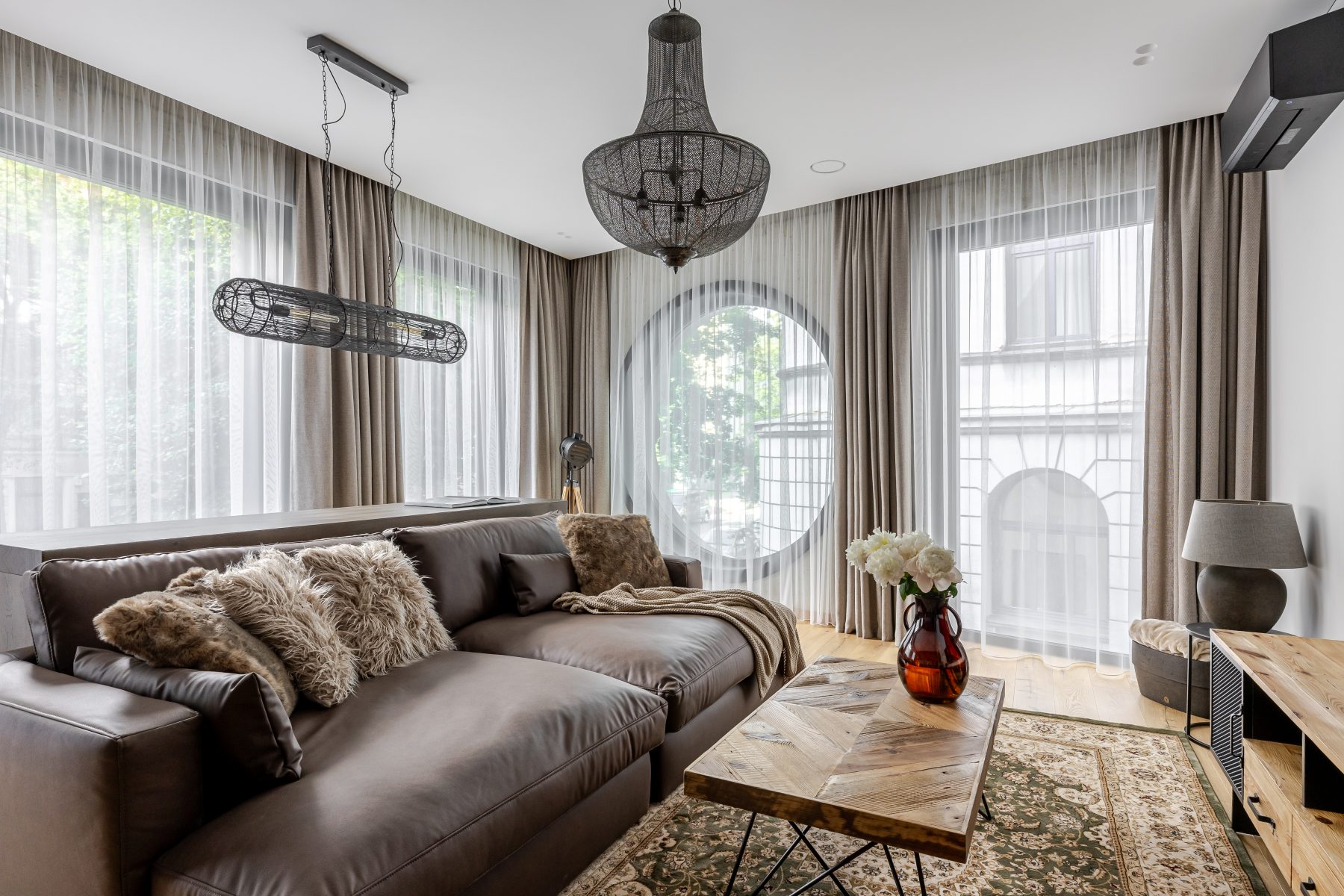 Šviesi moderni svetainė su dideliais langais ir natūralaus medžio detalėmis