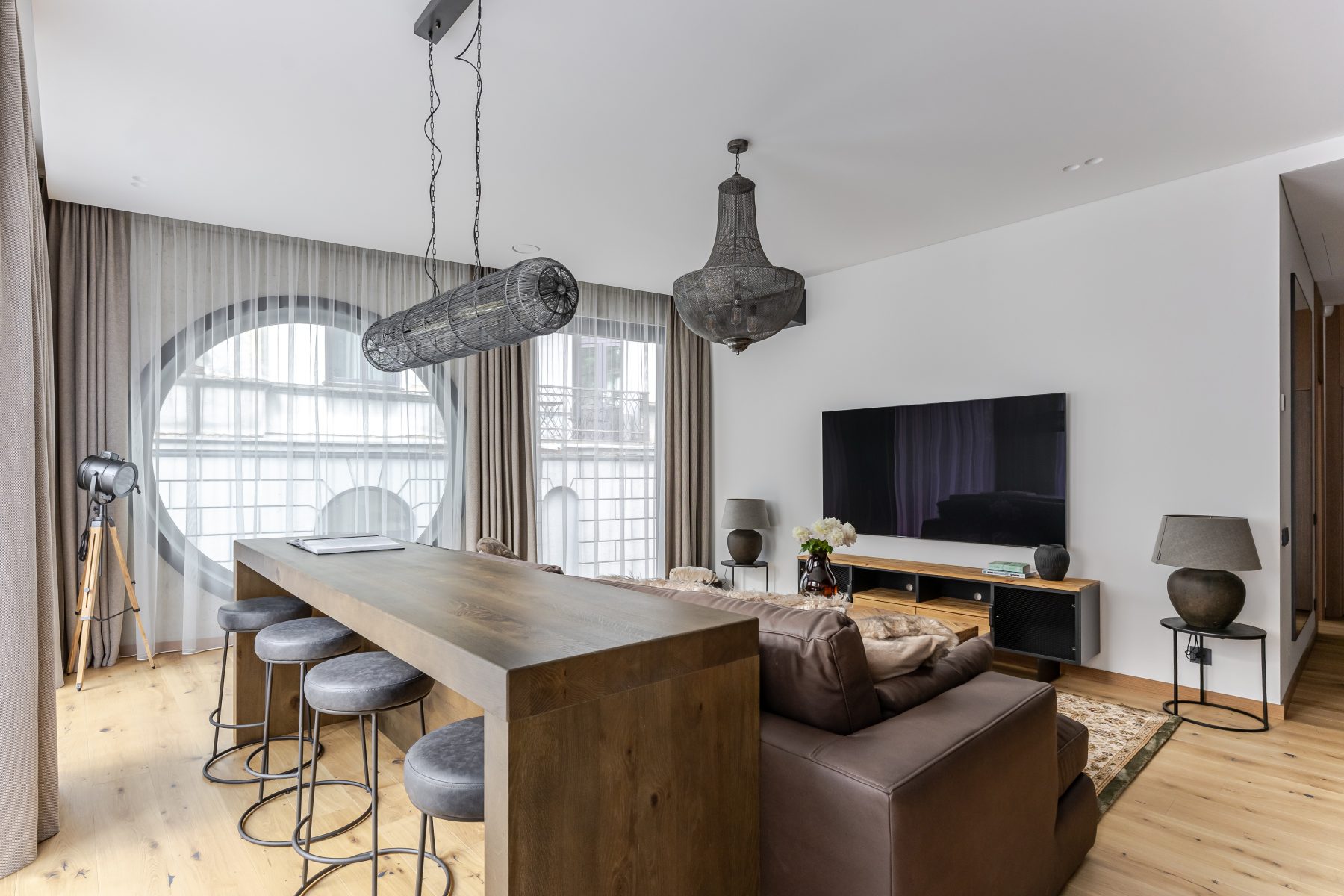 Šviesi moderni svetainė su dideliais langais ir natūralaus medžio detalėmis