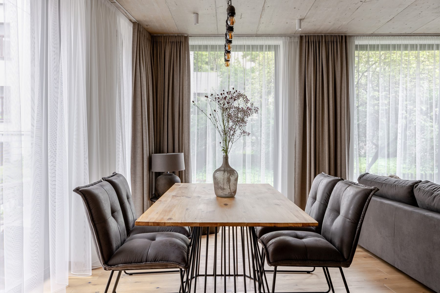 Erdvi svetainė su minkštais baldais, natūralaus medžio detalėmis ir dideliais langais