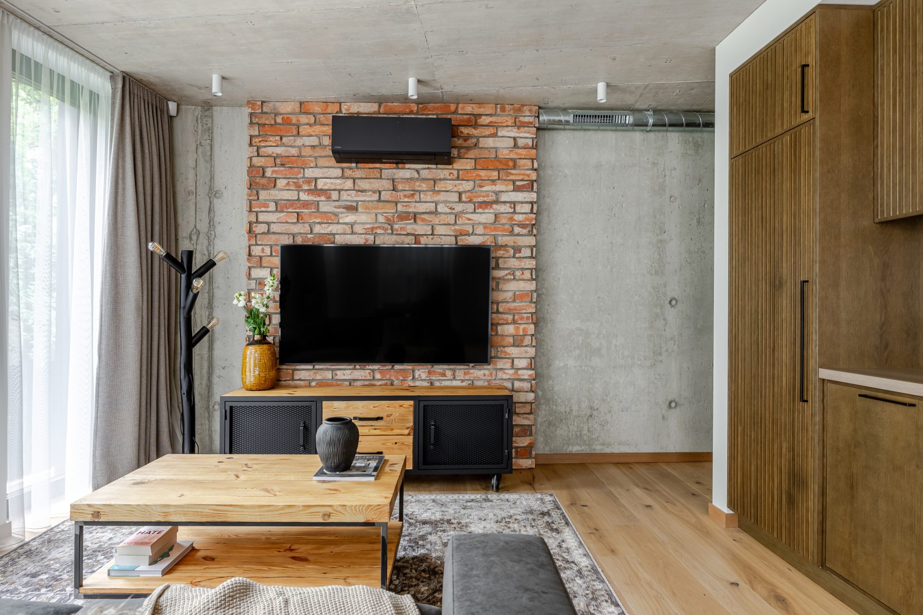 Erdvi svetainė su minkštais baldais, natūralaus medžio detalėmis ir dideliais langais