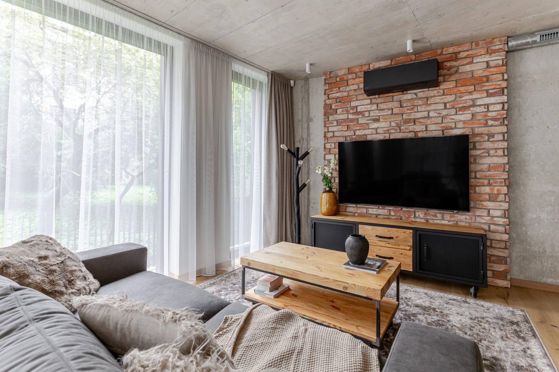 Erdvi svetainė su minkštais baldais, natūralaus medžio detalėmis ir dideliais langais