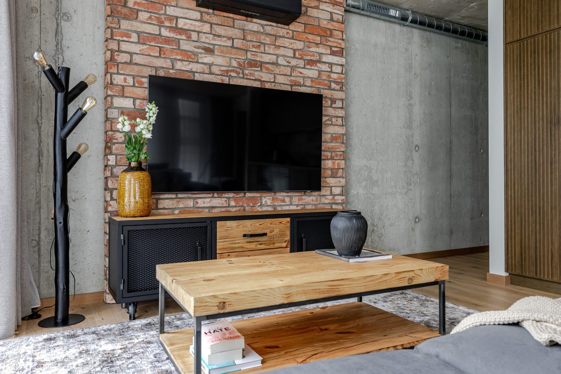 Erdvi svetainė su minkštais baldais, natūralaus medžio detalėmis ir dideliais langais