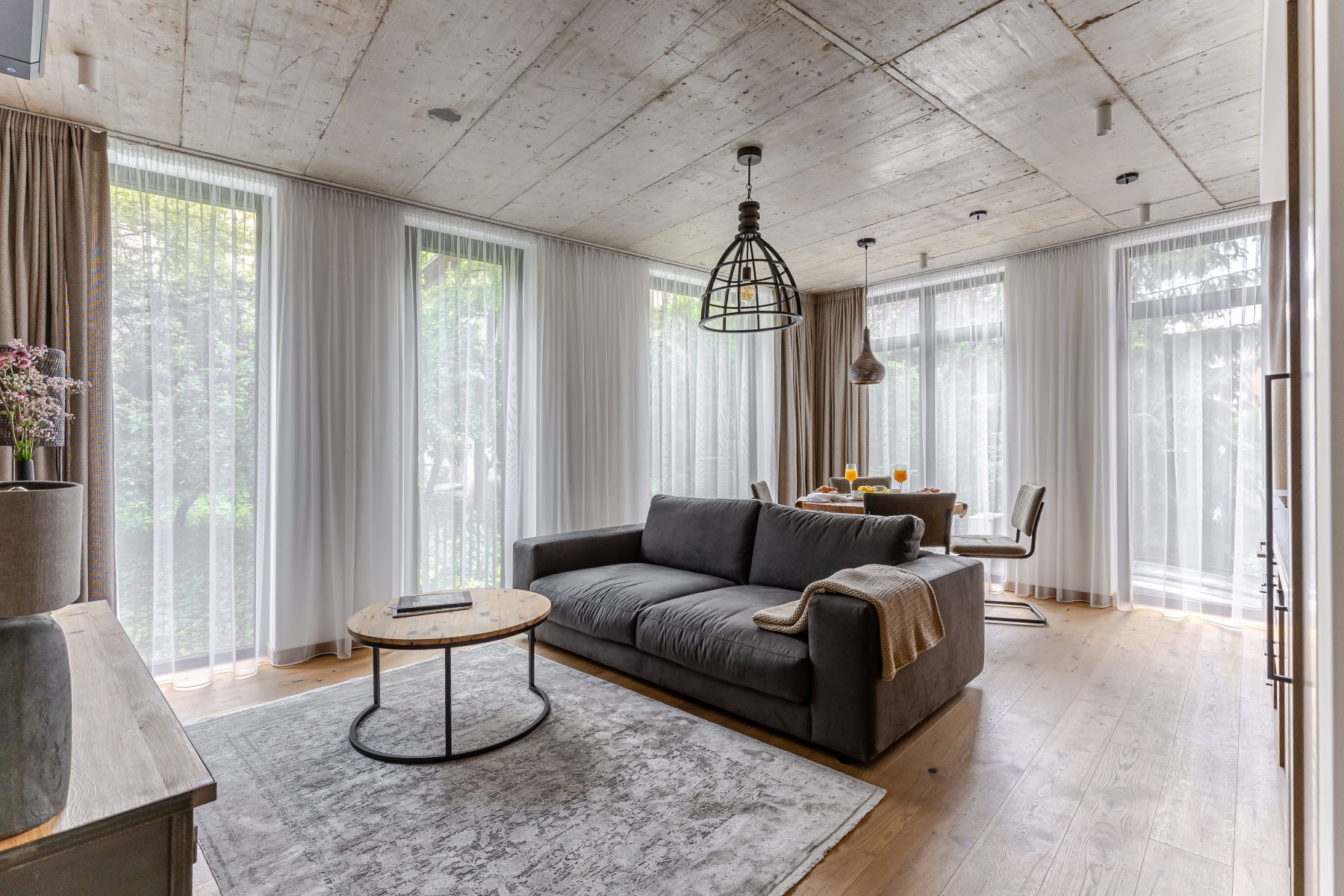 Moderni svetainė su dizaino baldais ir dideliais langais