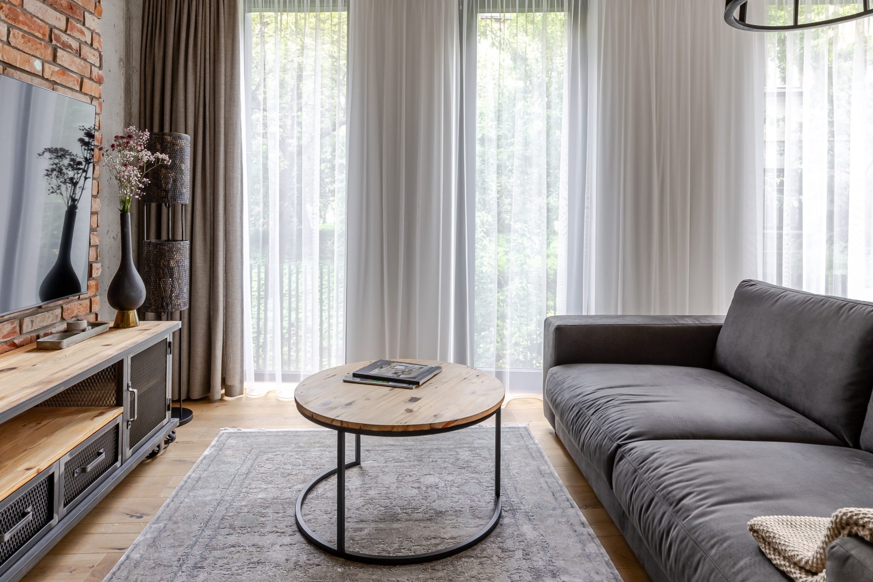 Moderni svetainė su dizaino baldais ir dideliais langais