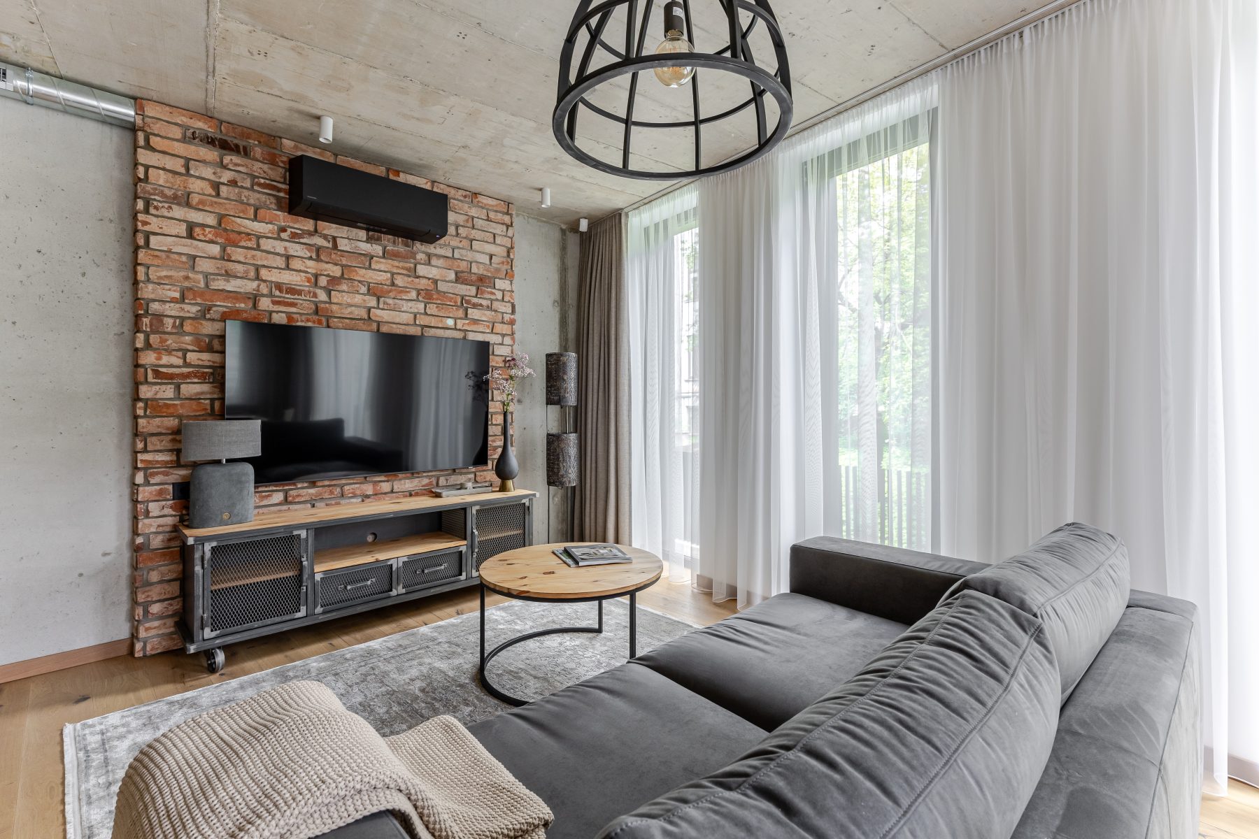 Moderni svetainė su dizaino baldais ir dideliais langais