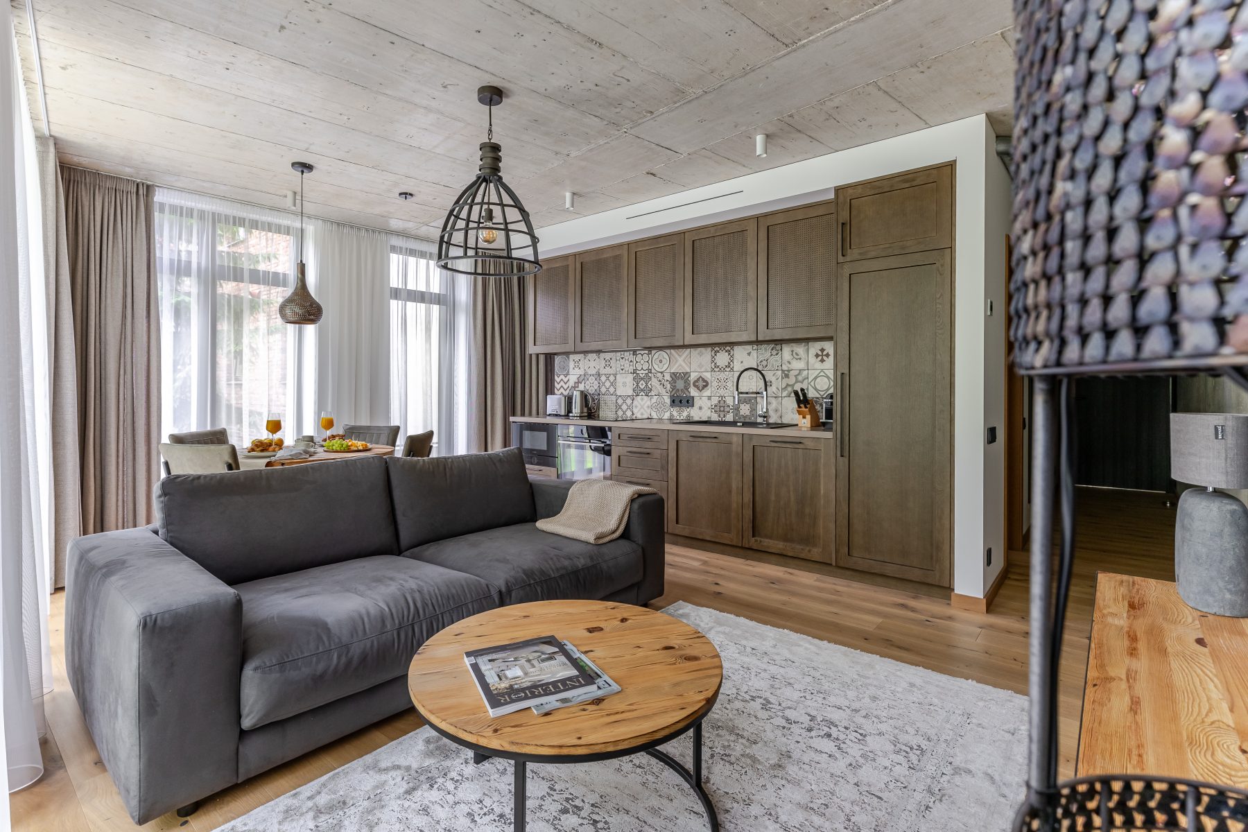 Moderni svetainė su dizaino baldais ir dideliais langais