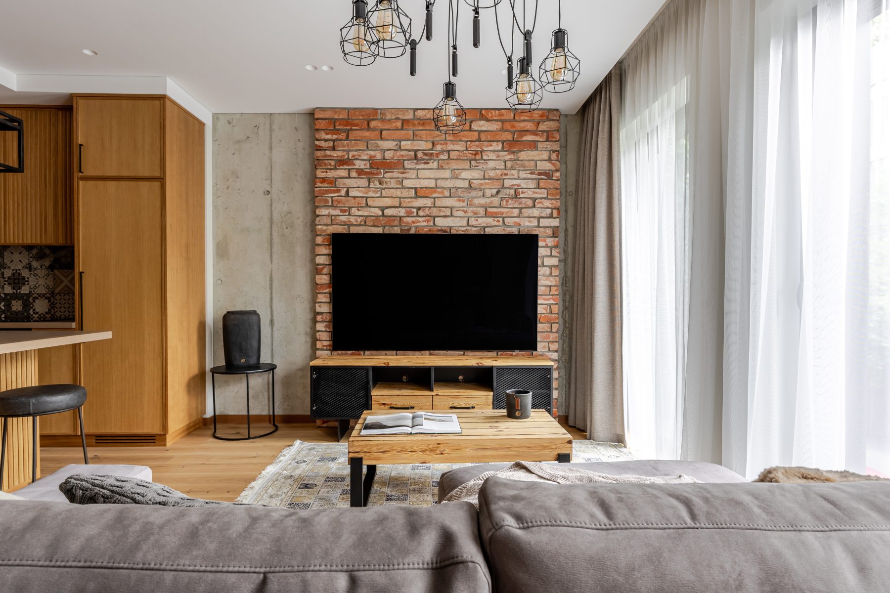 Šviesi svetainė su minkštais baldais ir medžio apdaila